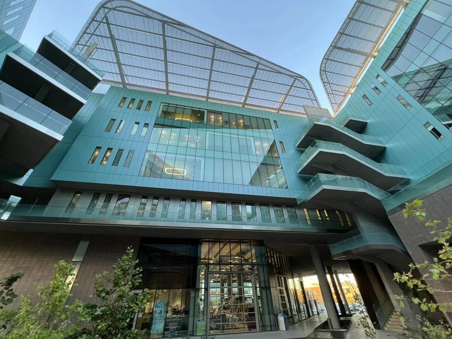 Upward view of the Walton Center for Planetary Health at Arizona State University, a glass-clad building with a sweeping steel canopy roof.